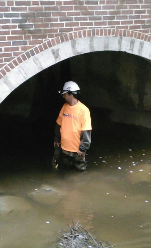 A stormwater manhole with a technician inspecting it.